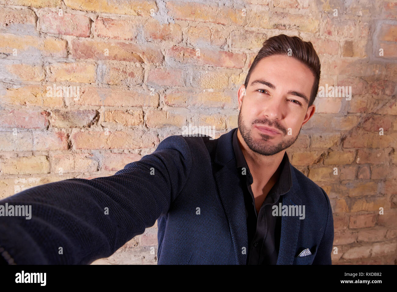 A smiling handsome young businessman talking a selfie with his ...