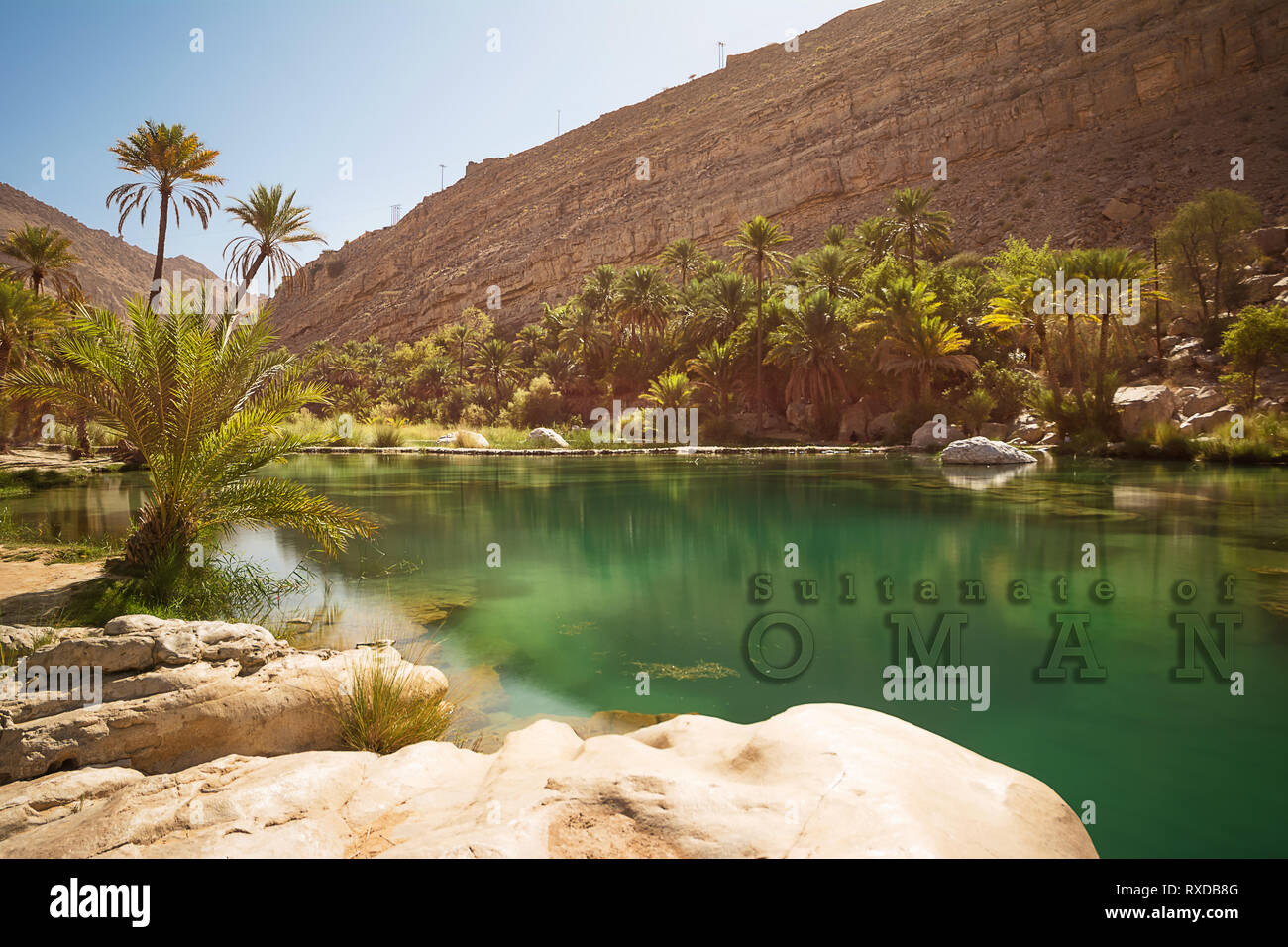 Wonderful lake and oasis with palm trees (Wadi Bani Khalid) in the Omani desert and overwritten text Stock Photo
