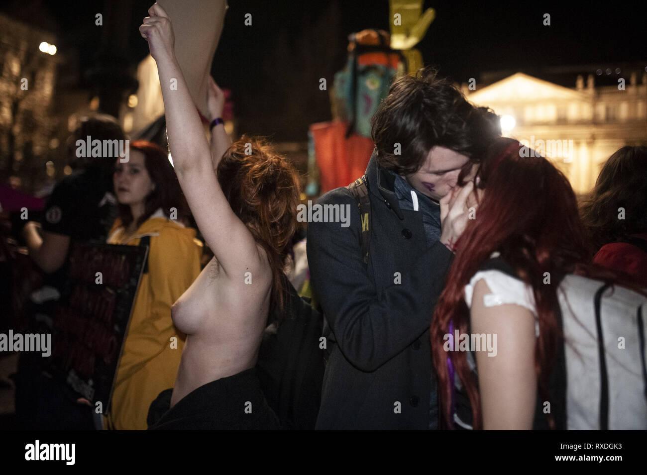 March 8, 2019 - Milano, Lombardia, Italy - A woman without a bra is seen  asking for body freedom next to a couple kissing during the protest..The  network Non Una di Meno