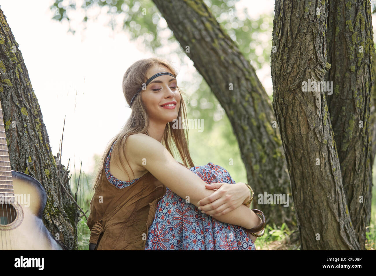 beautiful hippie girl sitting near trees in forest Stock Photo