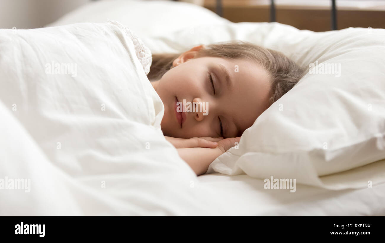 Calm kid girl sleeping in bed covered with warm duvet Stock Photo