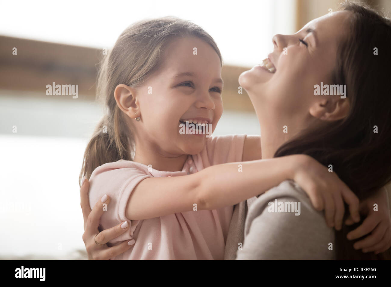 Cute kid girl and smiling mom laughing embracing cuddling together Stock Photo