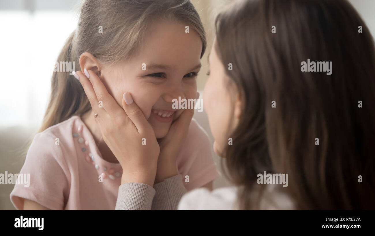 Loving mother touching face of smiling cute funny kid girl Stock Photo