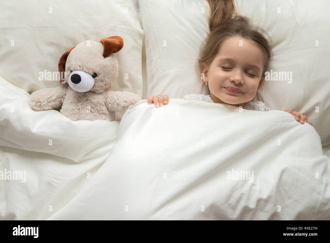 Happy cute kid sleeping with teddy bear in comfortable bed Stock Photo