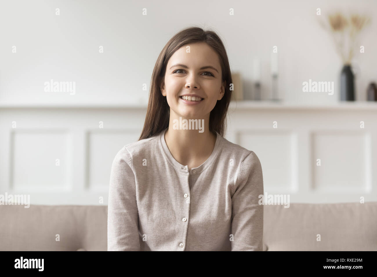 Smiling young casual woman sitting on couch looking at camera Stock ...