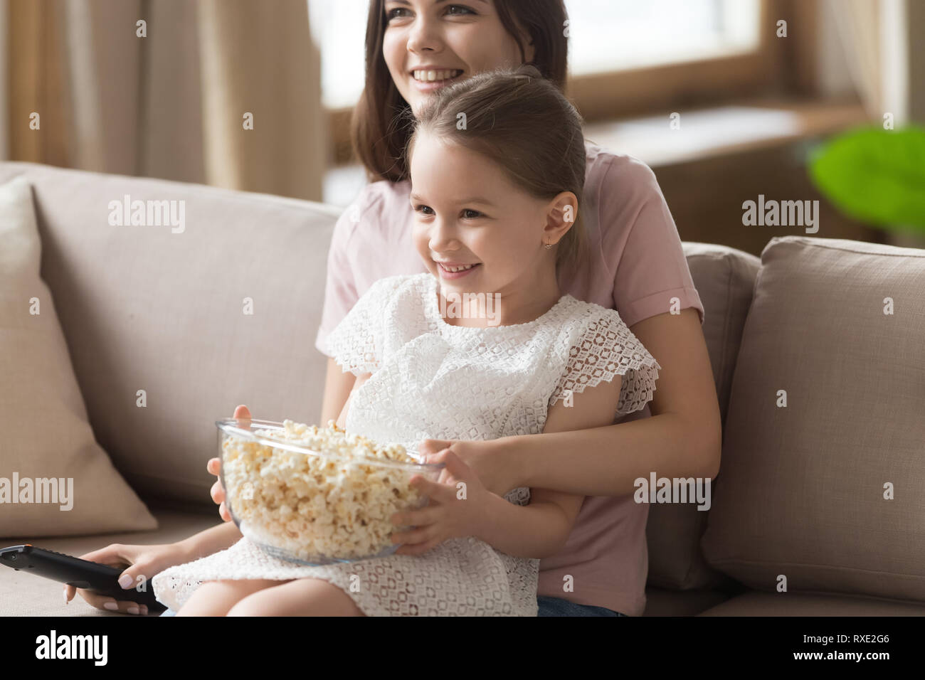 Happy family mom with cute kid daughter watching tv together Stock Photo