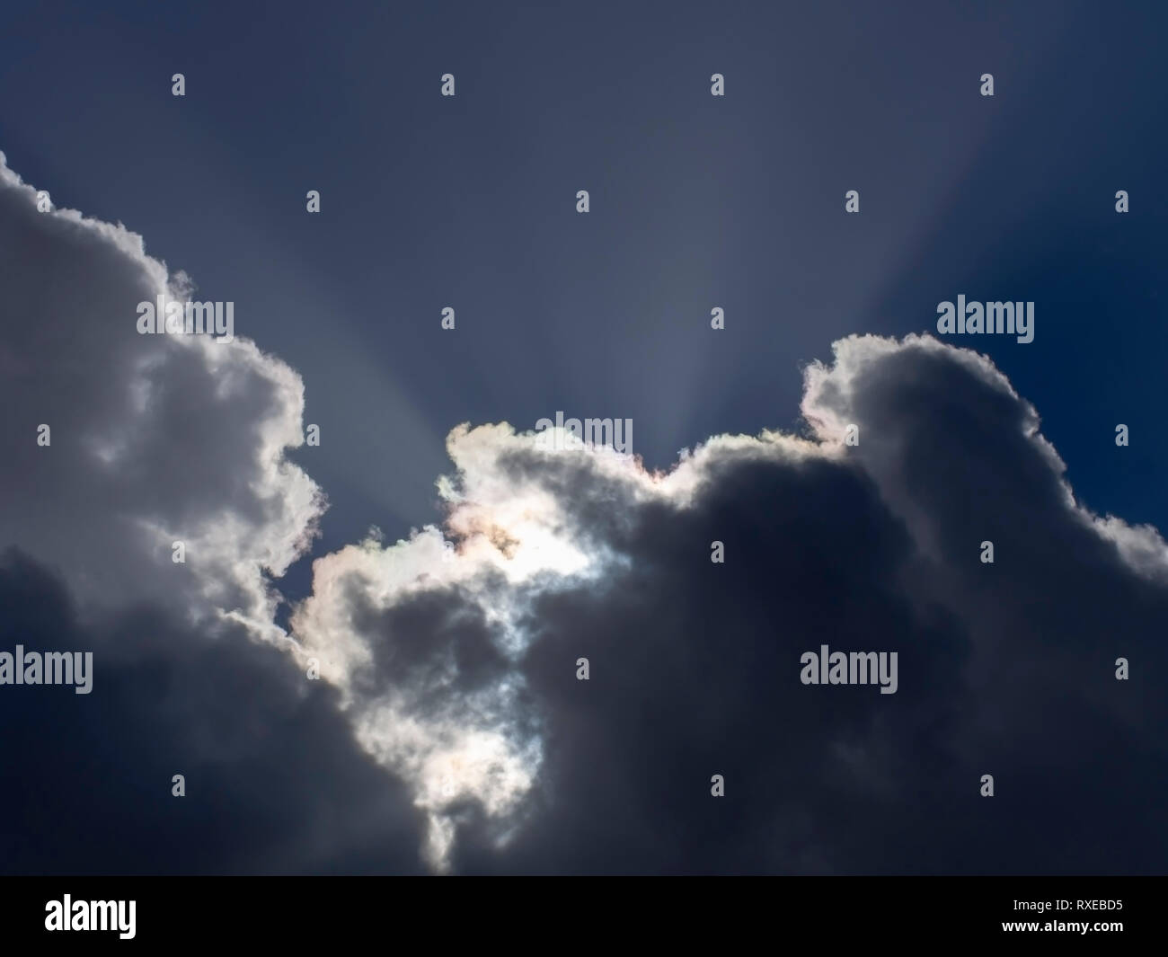 Fluffy white cumulus clouds with silver lining and sun rays. Weather or