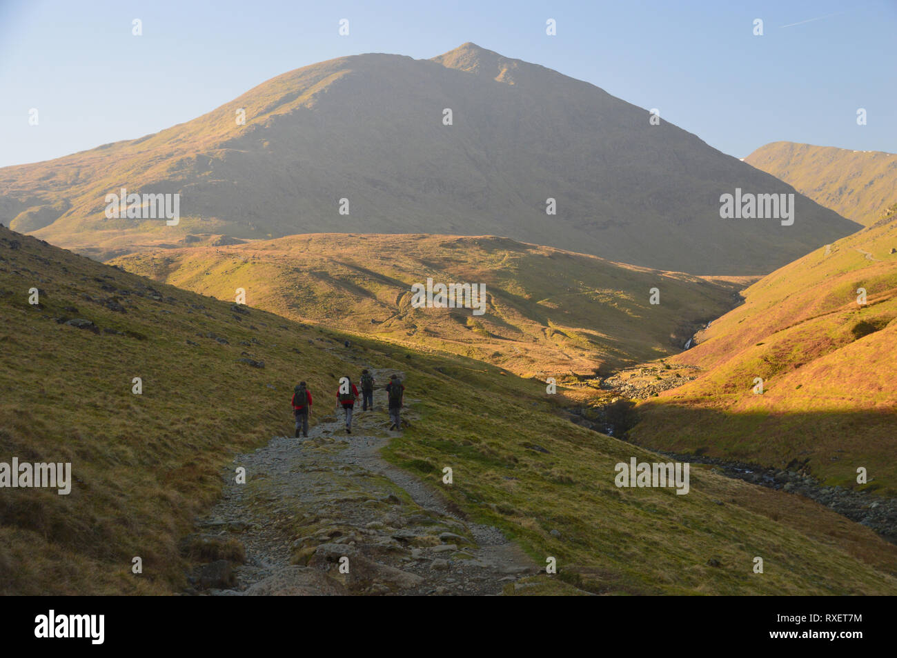 Four Hikers Walking Towards the Wainwright Catstycam from the Youth Hostel in Glenridding in the Lake District National Park,  Cumbria, England,  UK. Stock Photo