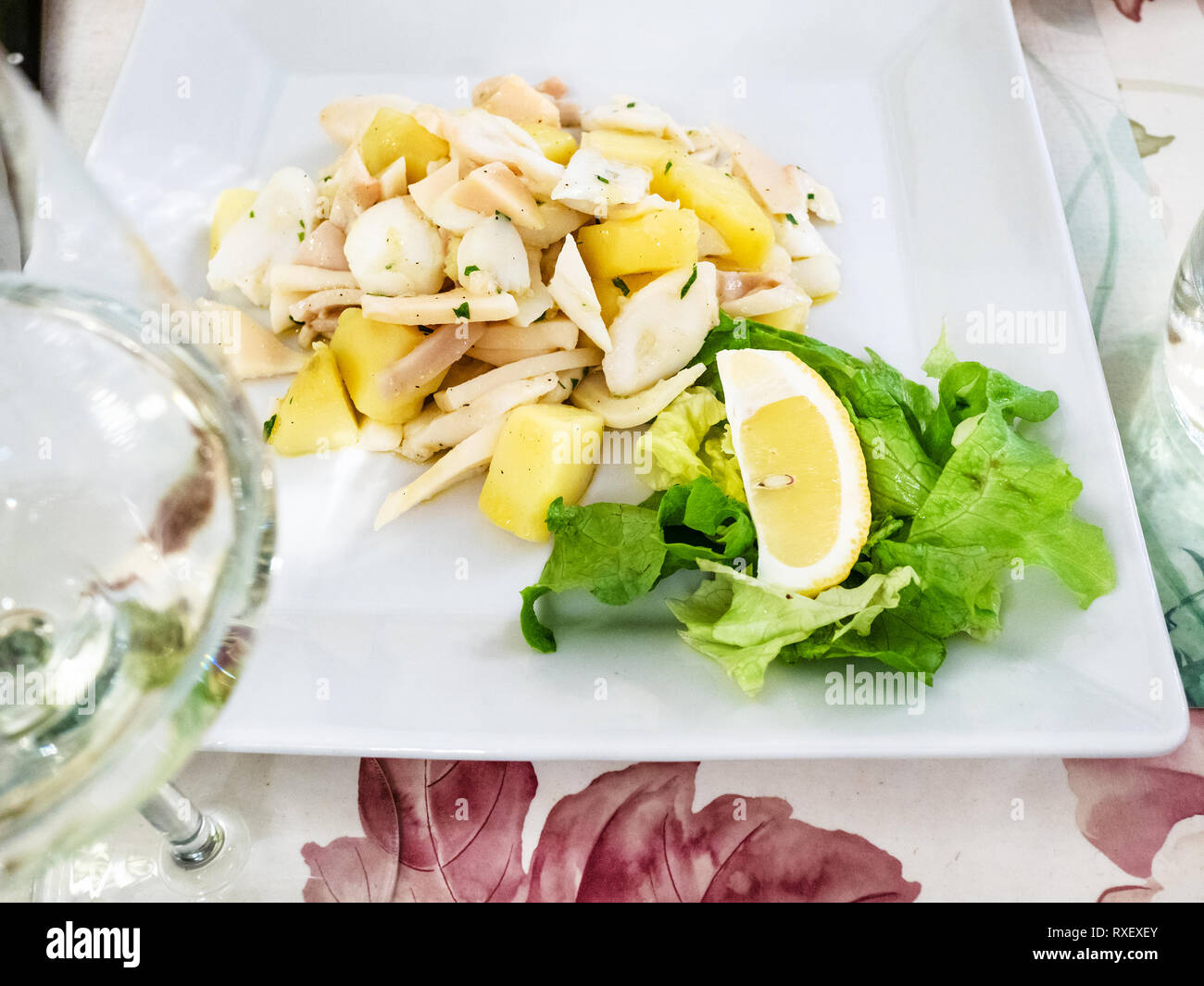 Italian cuisine - insalata di Polpo (salad from potato, octopus, squid and cuttlefish) on white plate in local restaurant in Lombardy Stock Photo