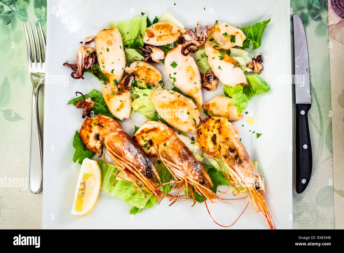 Italian cuisine - white plate with fried prawns and squids in local restaurant in Lombardy Stock Photo