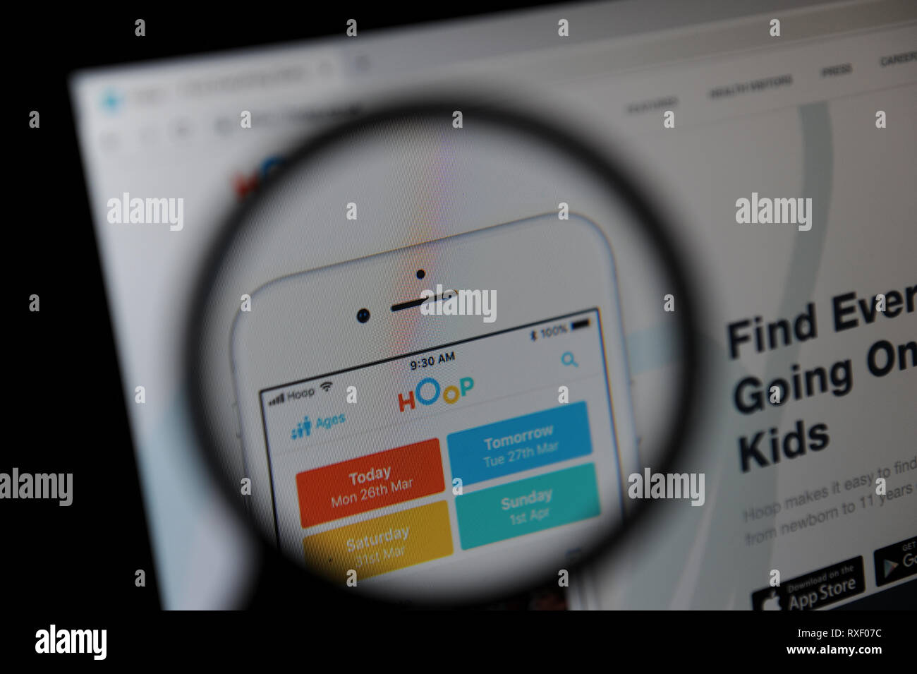 The Hoop website seen through a magnifying glass. Hoop is an app in which parents can book childrens activities. Stock Photo