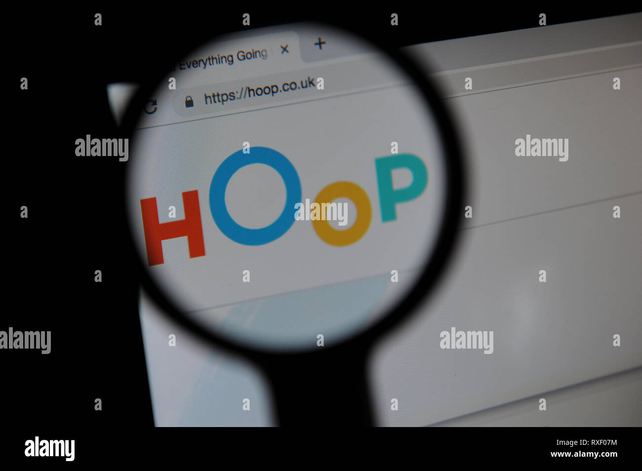 The Hoop website seen through a magnifying glass. Hoop is an app in which parents can book childrens activities. Stock Photo