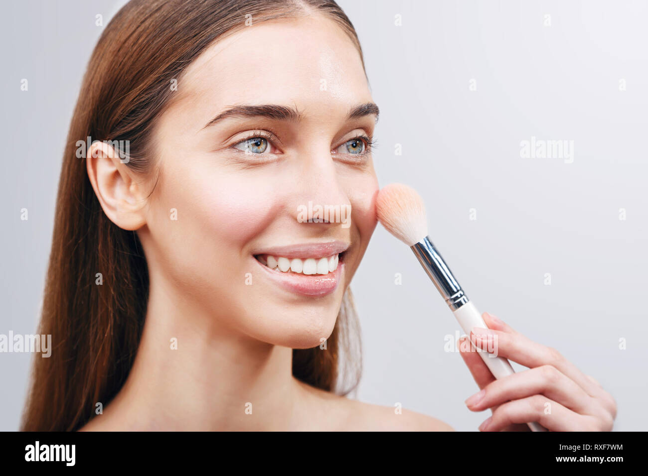 Closeup portrait of a woman applying dry cosmetic tonal foundation on