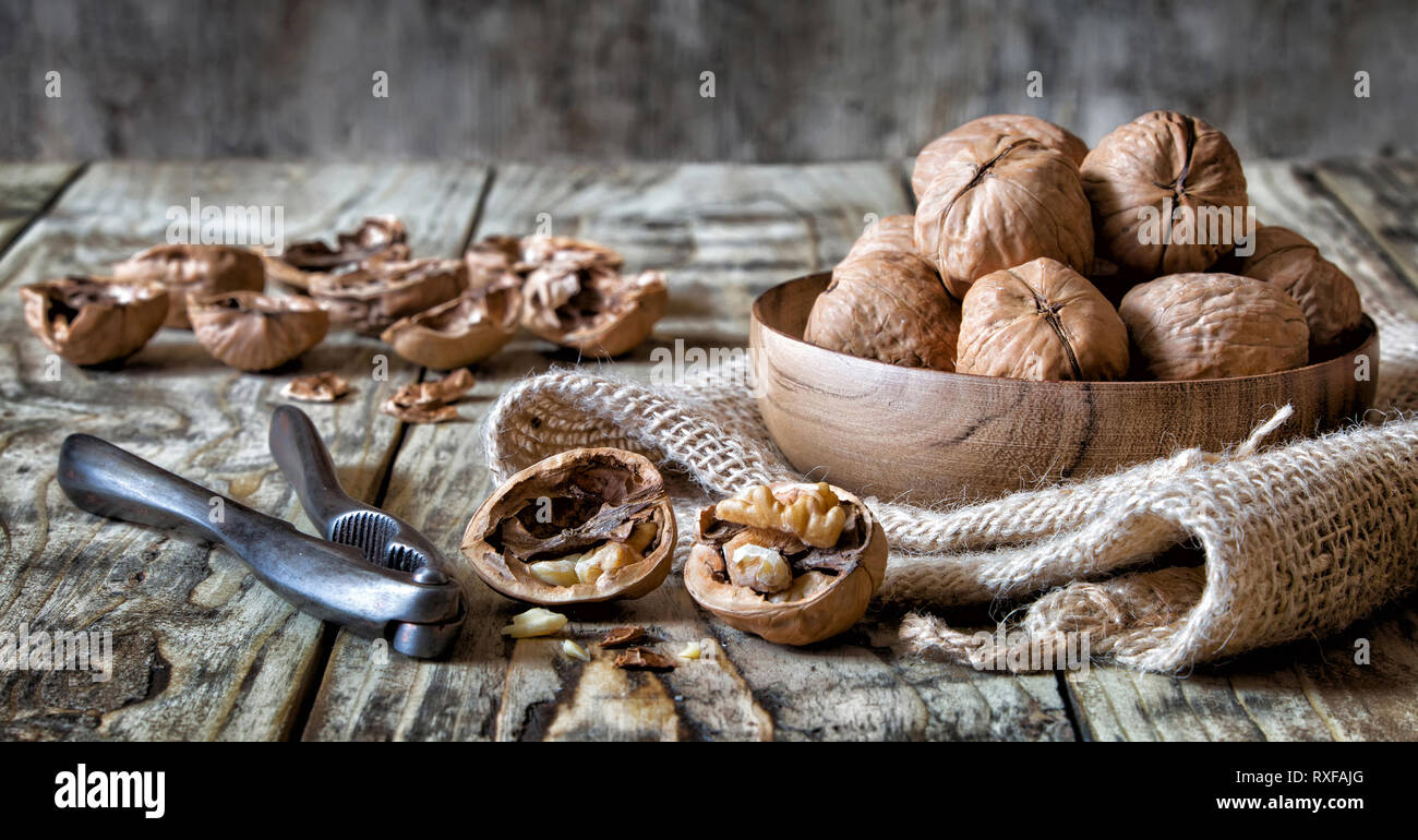 Walnuts in a bowl with nutcracker and cracked nuts Stock Photo