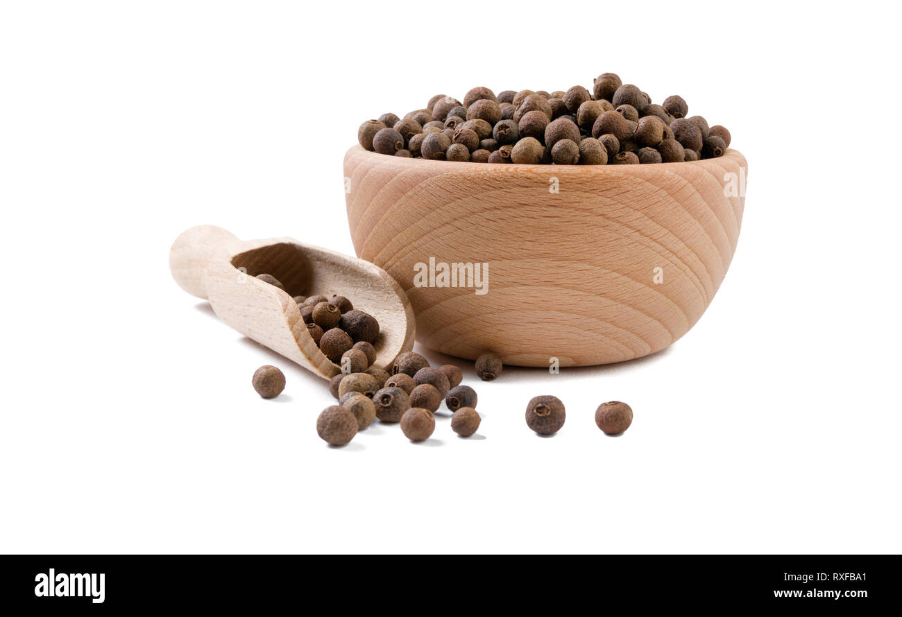 allspice in wooden bowl and scoop isolated on white background. Spices