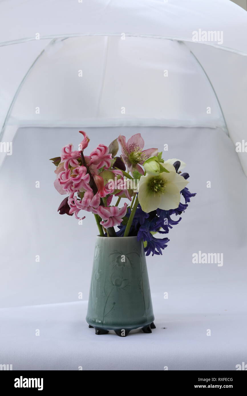 Bunch of spring flowers in a custom made ceramic vase with small feet Stock Photo