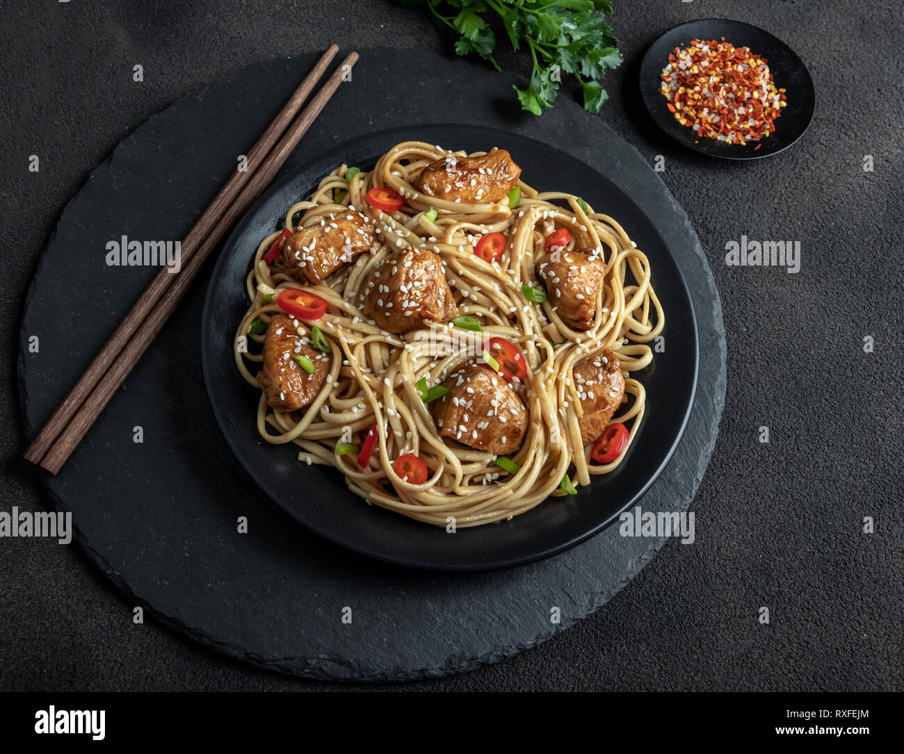 Asian noodles with chicken teriyaki , sesame, rustic stone background. Closeup. Chinese/Japanese