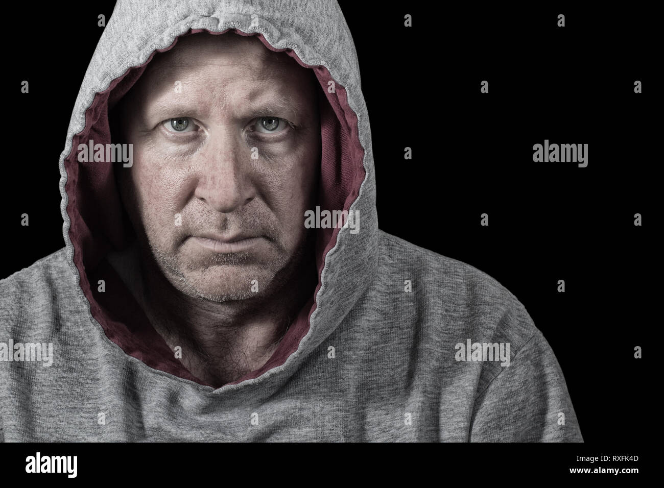 Unhappy and perhaps angry man in hoodie. Isolated on black. Stock Photo