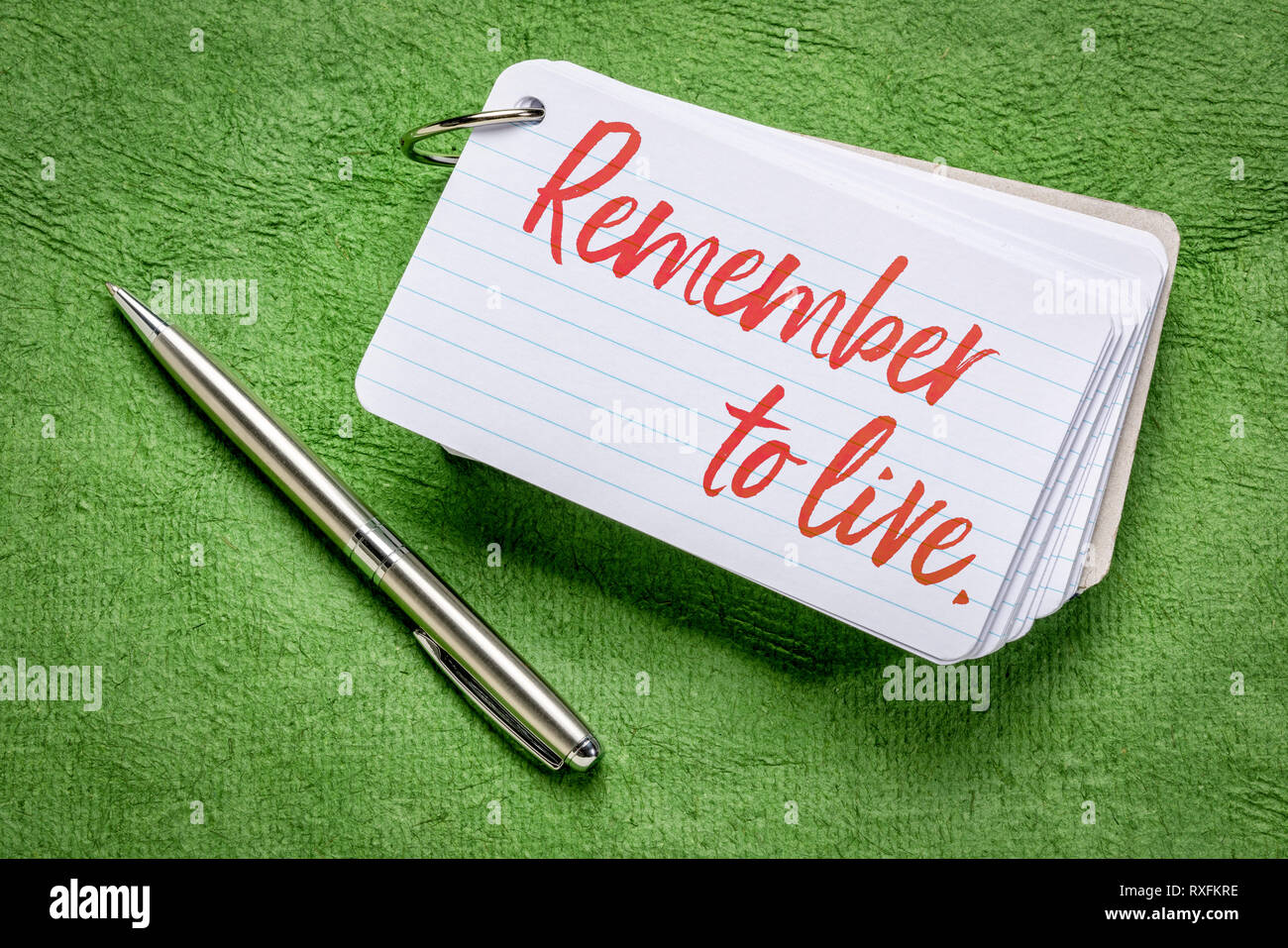 emember to live reminder - handwriting on an index card with a pen against green textured paper Stock Photo