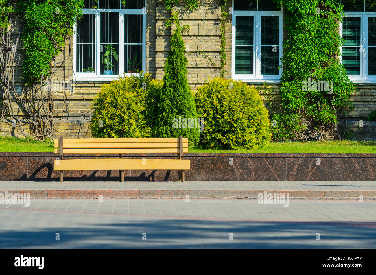 The Urban Invironment- Wooden Bench in Front of the Brick Facade of an ...