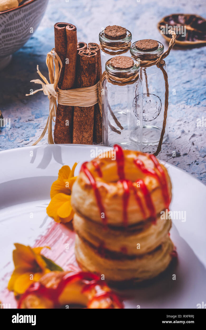 Vertical photo with few cinnamon sticks bonded by natural cord. Spicy sticks are placed next to three small glass bottles closed by cork seal. Glasses Stock Photo