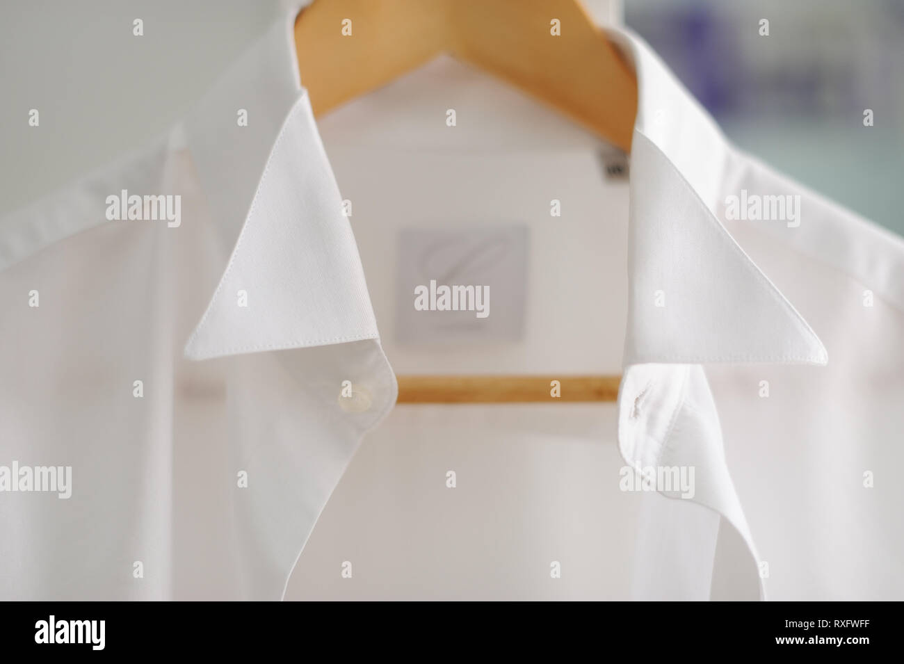 closeup detail of white shirt hanging on brown wooden hanger Stock Photo