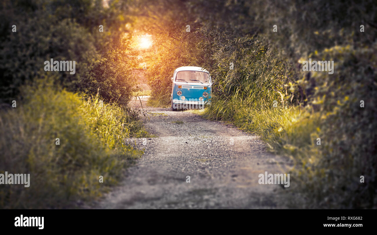 hippie bus on the road in sunset Stock Photo
