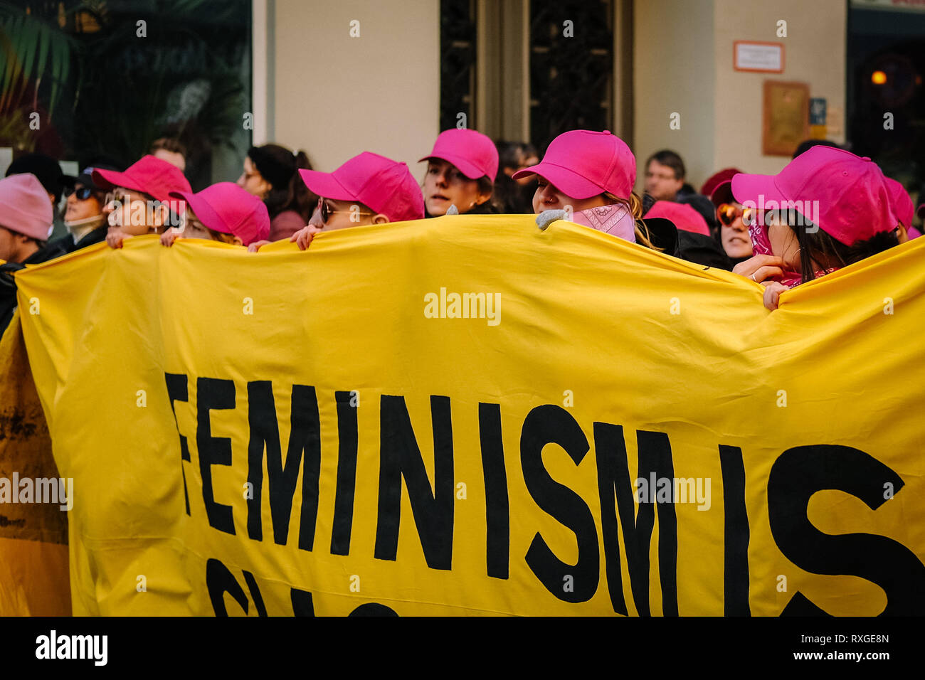 Women wearing pink caps are seen holding a banner during the protest. Thousands of people celebrate the international women´s day with protests demanding for women rights in berlin. Stock Photo