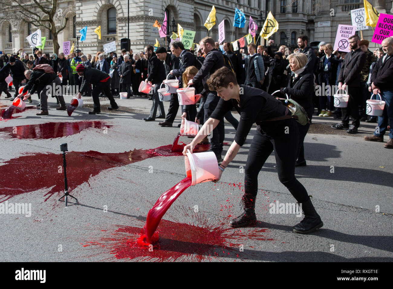 London, UK. 9th March, 2019. Climate activists from Extinction Rebellion pour artificial blood on the ground outside Downing Street as part of an act of civil disobedience named 'The Blood of Our Children' to call on the Government to take immediate steps to combat the current climate and ecological emergency. Stock Photo