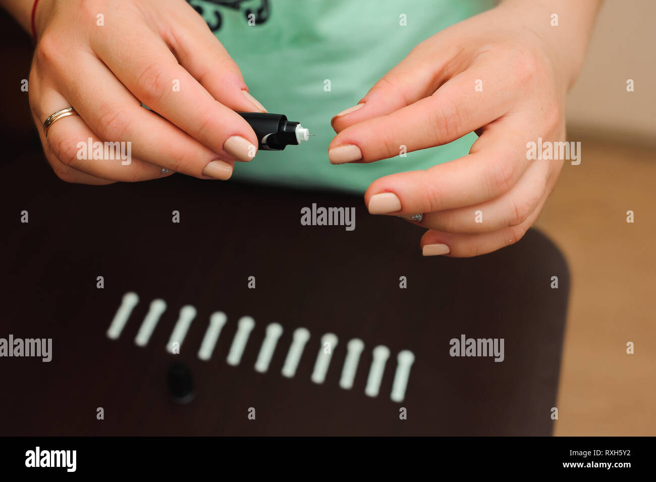 Woman taking blood sample with lancet pen on wooden background