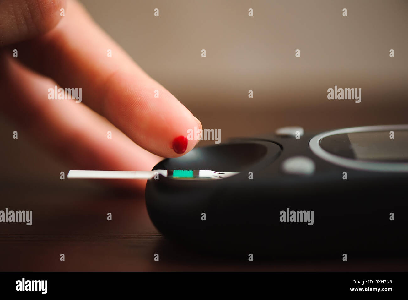 close up of male finger with blood drop and test stripe to checking