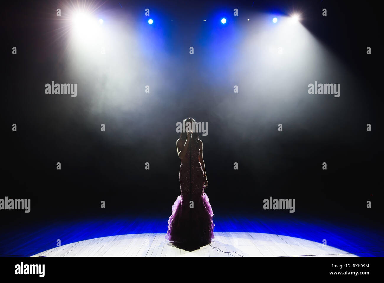 Female singer on the stage holding a microphone Stock Photo - Alamy