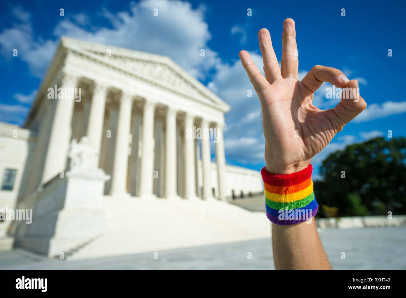 Hand wearing gay pride rainbow wristband making okay gesture outside the Supreme Court building in Washington, DC, USA Stock Photo