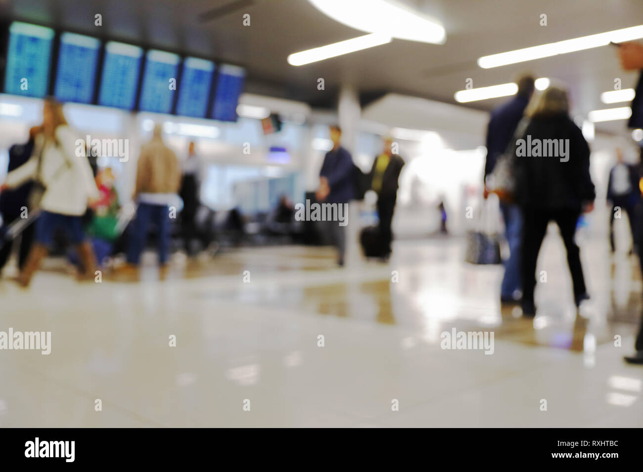 Defocus blurred bokeh of travelers in airport terminal traveling for work and vacation - suitcases, luggage, backpacks, digital flight schedule board Stock Photo