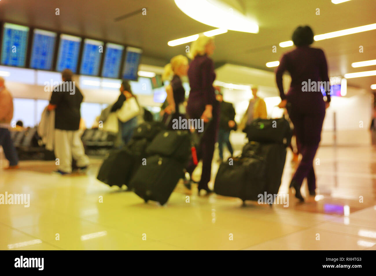 Defocus blurred bokeh of travelers in airport terminal traveling for work and vacation - suitcases, luggage, backpacks, digital flight schedule board Stock Photo