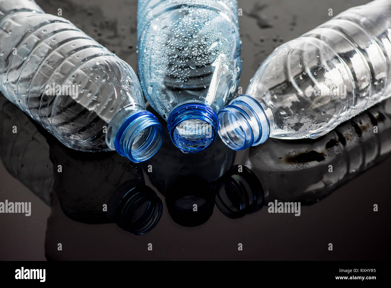 Wet background with a glass of water and empty plastic bottles Stock