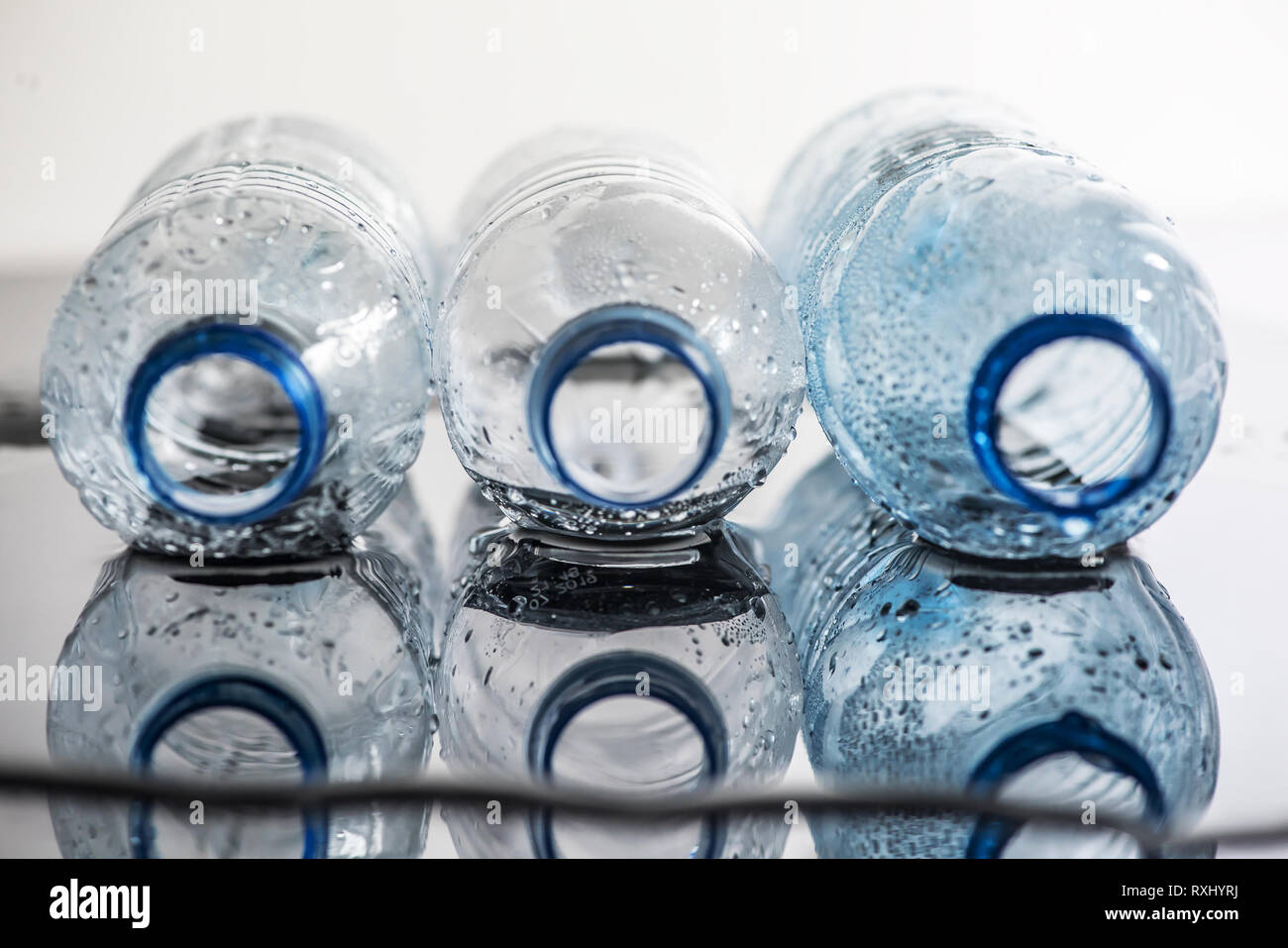 Wet background with a glass of water and empty plastic bottles Stock
