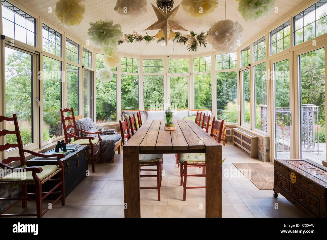 Recycled Teak Wood Dining Table With Red Wood And Woven Rawhide Seat Chairs In Solarium With Wood Imitation Ceramic Tile Floor Inside An Old 1826 Cottage Style Fieldstone House Quebec Canada This