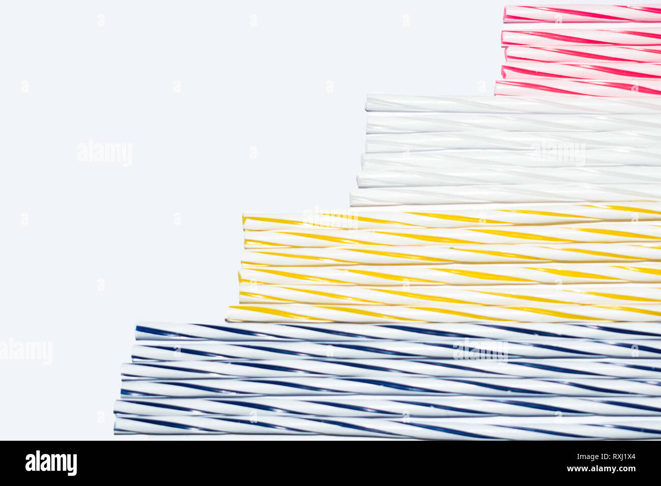 Blue, yellow, white and red stripes of thin candles on a white background, concept Stock Photo