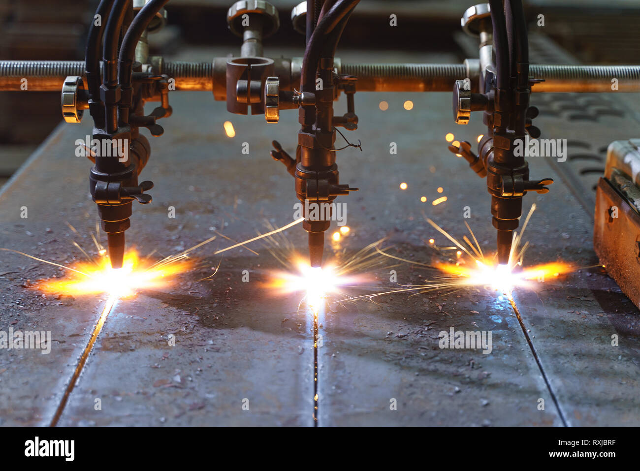 The machine cuts metal sheets with gas. Flying spray molten metal. Side  view. three gas cutter nozzles Stock Photo - Alamy