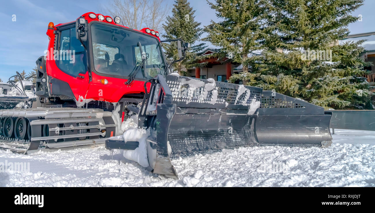 Red snow groomer on a sunlit snow covered ground Stock Photo