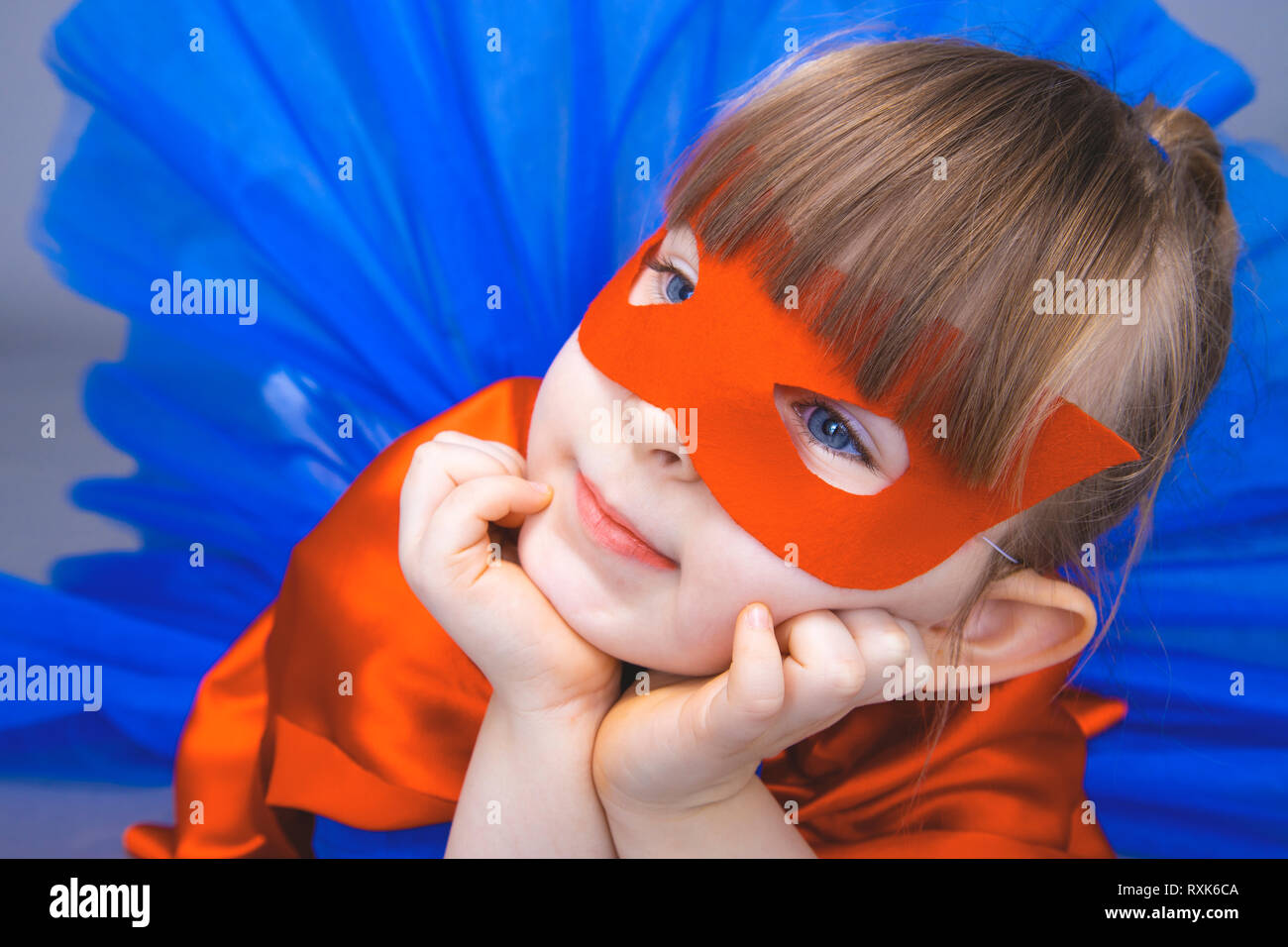 Little girl superhero in a red cloak and mask Stock Photo