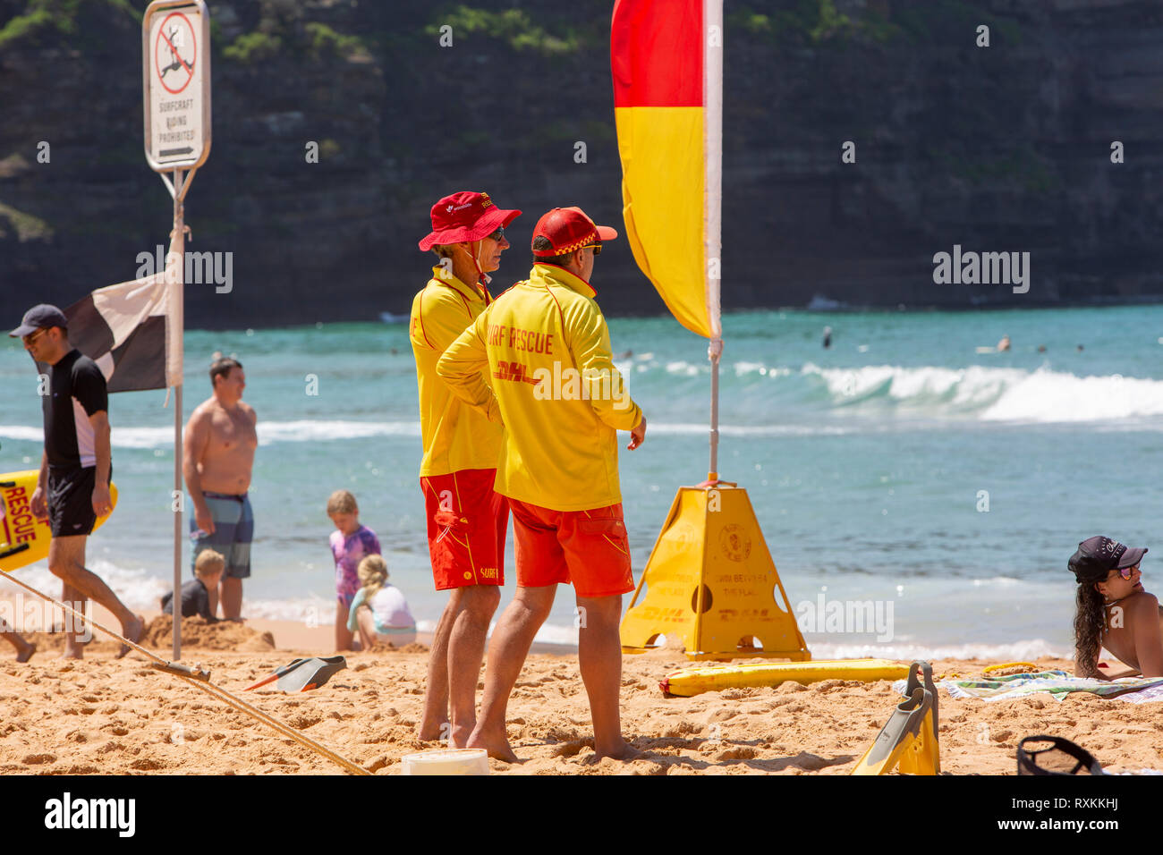 Volunteer surf rescue personnel stood by yellow and red flags on Bilgola beach,Sydney,Australia Stock Photo