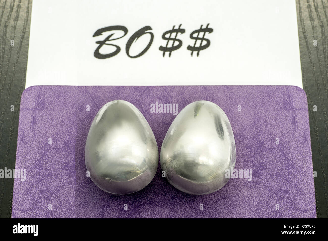 Two metal eggs on the office desk opposite the word Boss. The concept of power Stock Photo