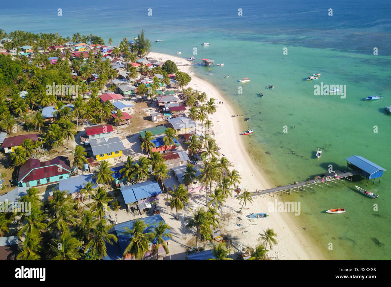 Aerial drone view of long white sandy beach tropical island with Malay traditional fisherman village. Mantanani Island Sabah Malaysia Borneo. Stock Photo