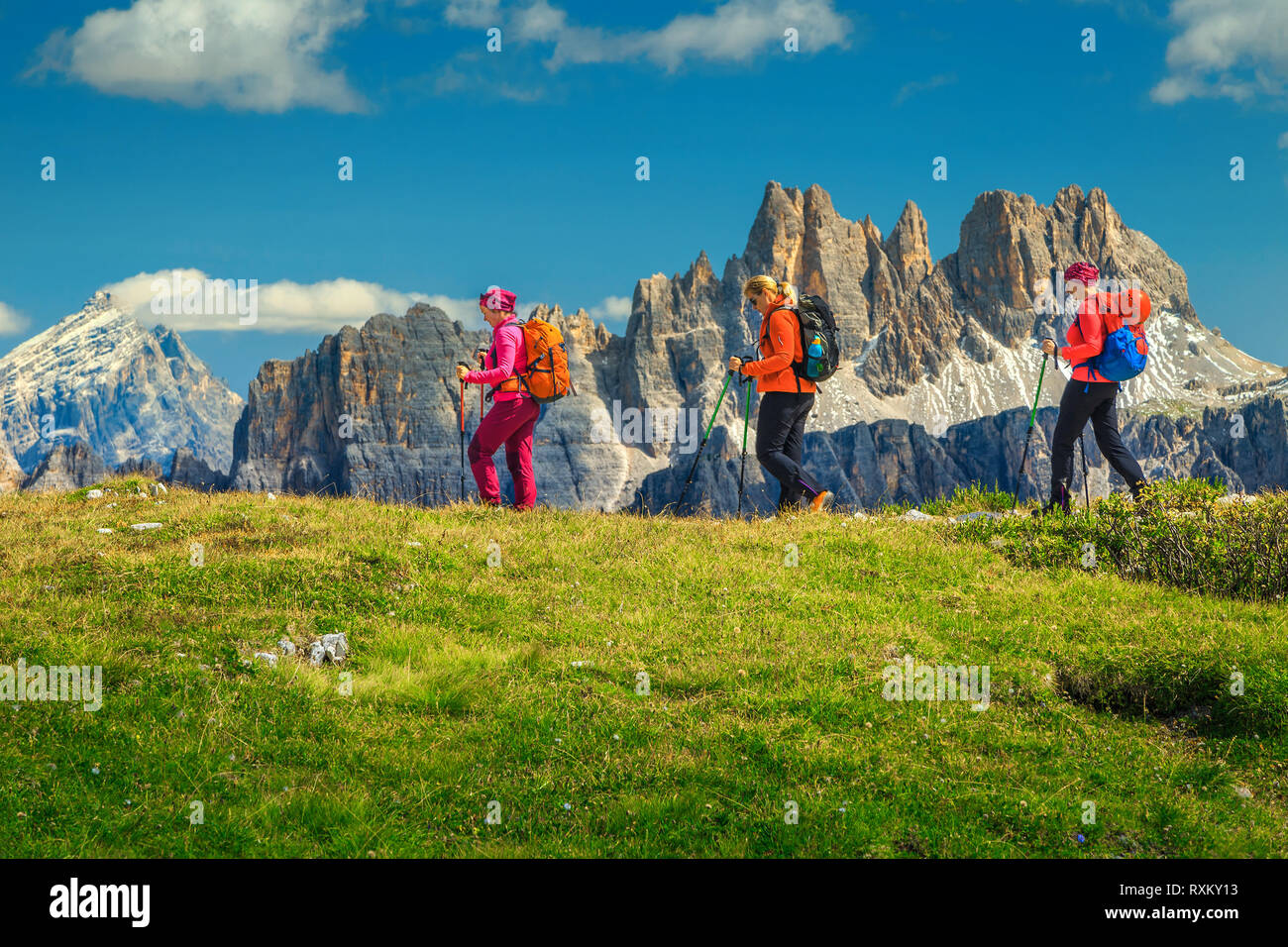 Sporty healthy active woman group of hikers with colorful backpacks and mountain equipment walking on the mountain ridge, Dolomites, Italy, Europe Stock Photo