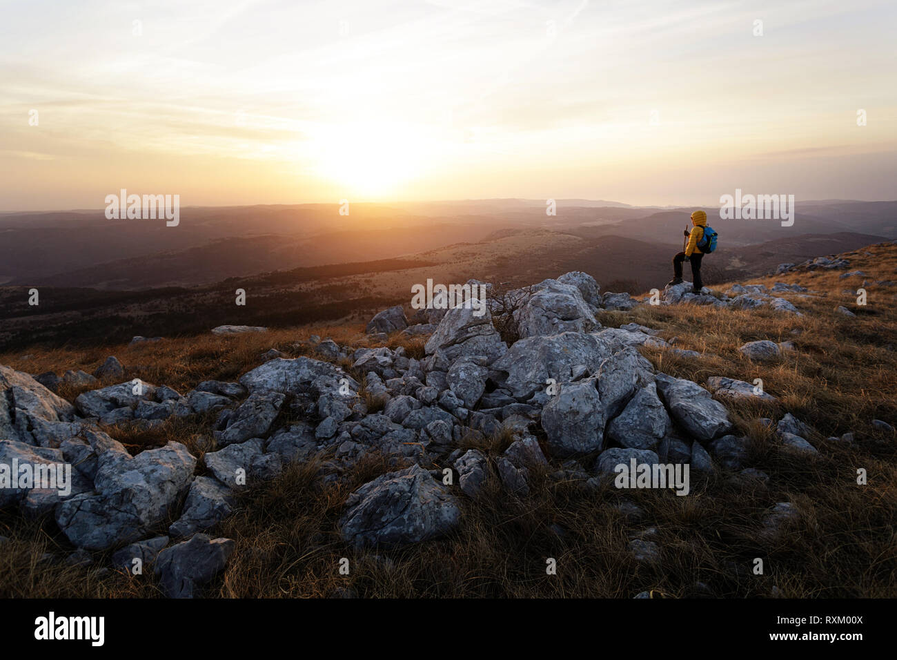 Boy hiking on a grass covered mountain at sunset, Golic, Slovenia Stock Photo