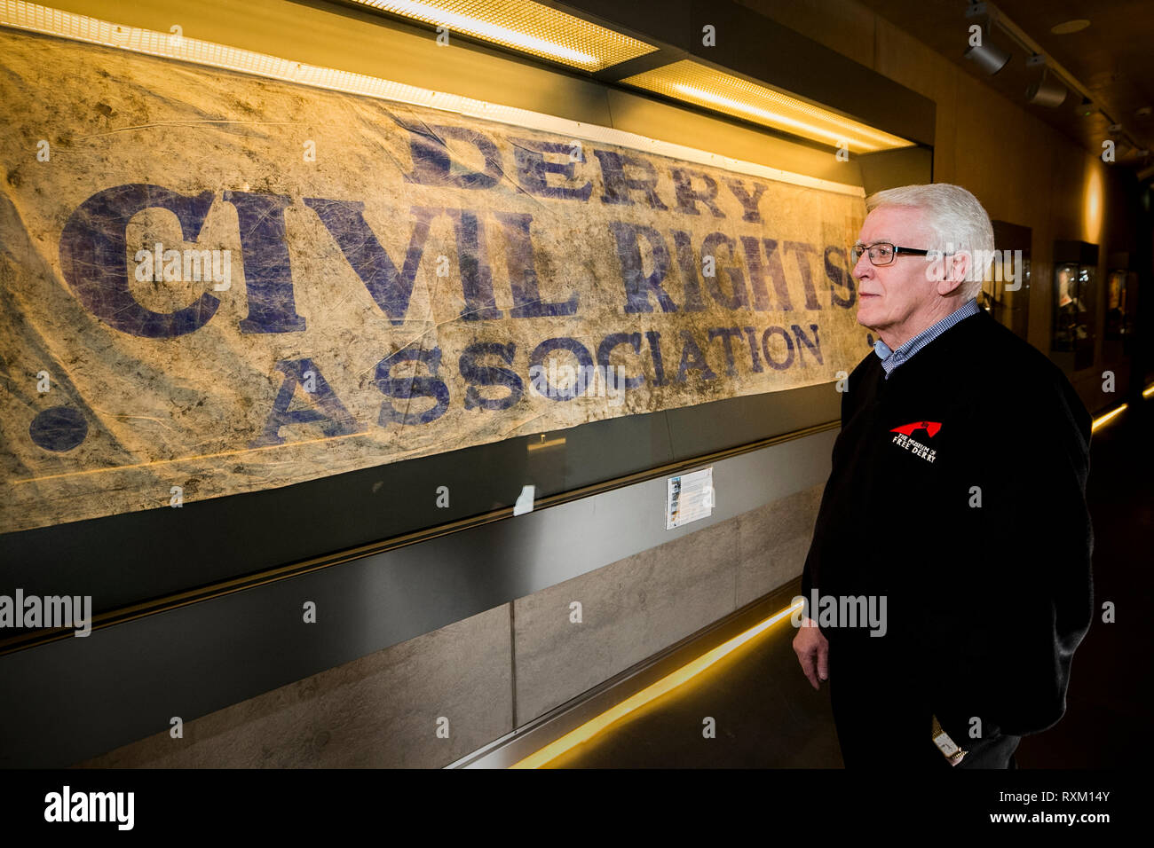 John Kelly whose 17 year old brother, Michael, was killed during Bloody Sunday stands beside the Derry Civil Rights Association banner in The Museum of Free Derry that was carried on the day which is known as Bloody Sunday. The Public Prosecution Service is expected to announce whether it will pursue prosecutions against soldiers over the deaths of 13 people in Londonderry on January 30 1972. Stock Photo