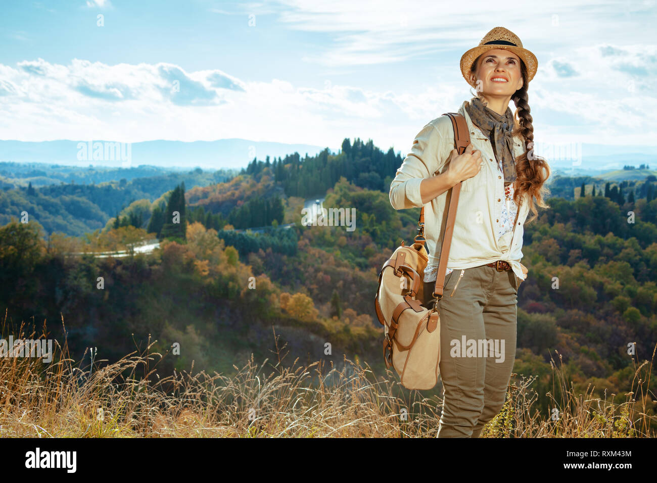 https://c8.alamy.com/comp/RXM43M/smiling-fit-traveller-woman-in-hiking-clothes-with-bag-on-summer-tuscany-trekking-looking-into-the-distance-RXM43M.jpg
