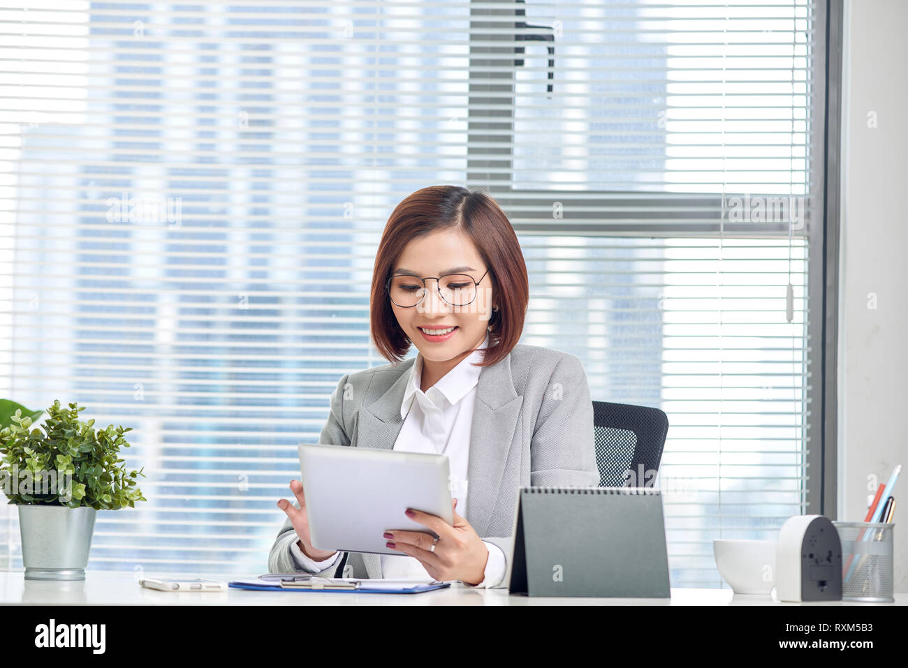 Asian businesswoman working with tablet computer at office desk. Stock Photo
